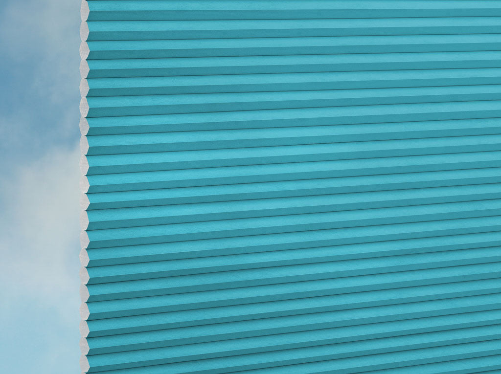 Nahaufnahme der DUETTE® Fixé Unix (1.7646) Türkis-Jalousien von Duetteshop mit türkisfarbenem Wabenmuster vor einem sanften hellblauen Hintergrund, der die detaillierte Textur und Struktur hervorhebt.