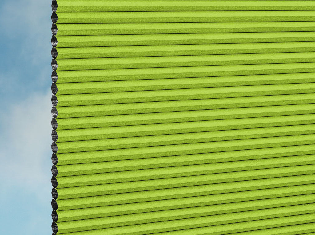 Nahaufnahme der DUETTE® Fixé Unix Dark (3.7472) Grün Jalousien von Duetteshop mit einem Wabenmuster, das teilweise einen strahlend blauen Himmel und sanfte Wolken im Hintergrund zeigt.