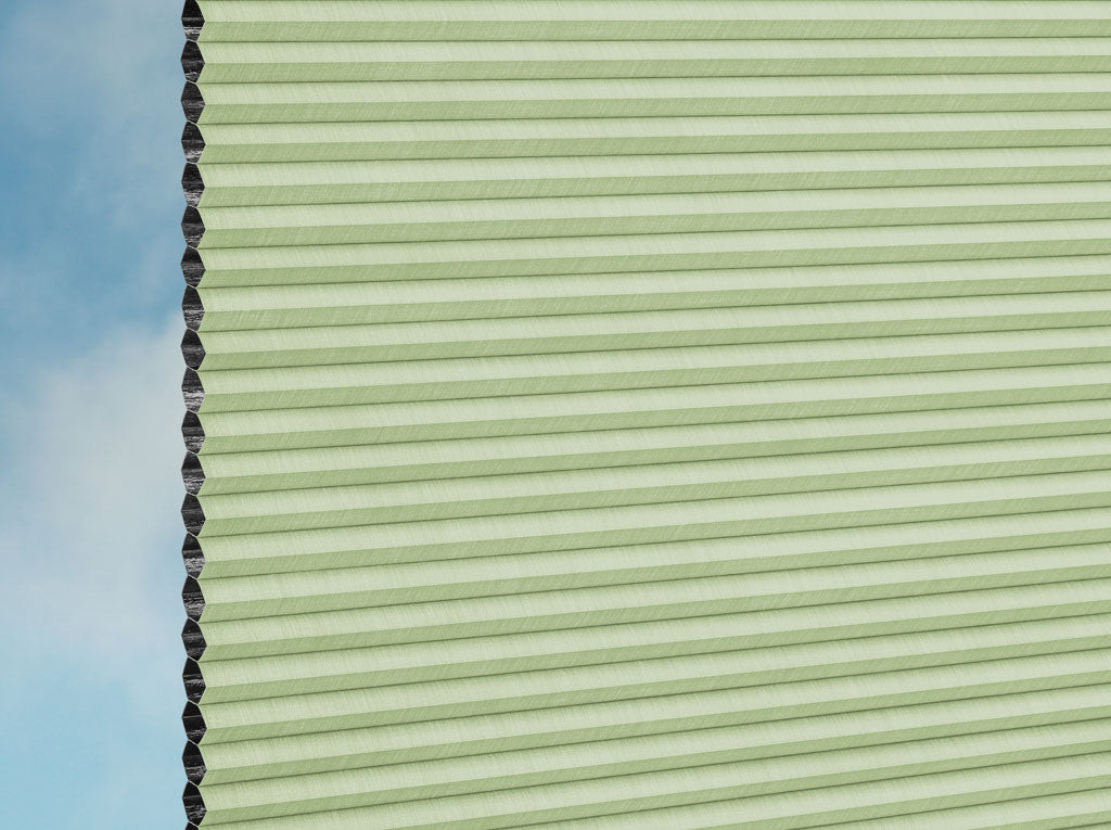 Nahaufnahme von DUETTE® Fixé Elan Dark (4.3773) Grüner Zellwabenschirm von Duetteshop mit hellgrünen Falten und schwarzem Rand vor blauem Himmel, der das strukturierte und isolierende Design hervorhebt.